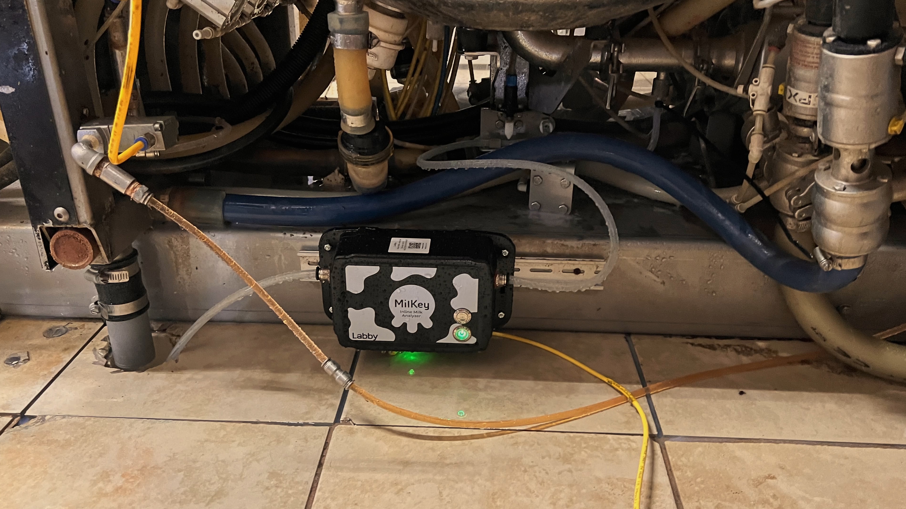 Close-up of MilKey inline sensor with green status LED on milk pipeline